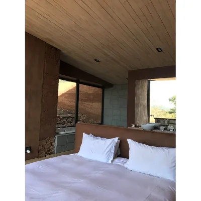 Witklipfontein Eco lodge with views of the outdoor landscape that reflect in the earthy hues of the bedroom suite with crisp white linen, brown leather headboard and sand textured walls with palette wood, bleached with lime for the ceilings.