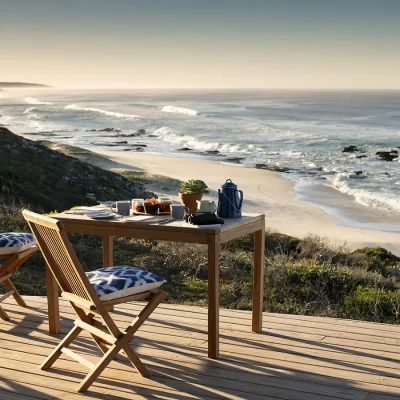 Wooden deck with outdoor wooden table and chairs overlooking De Hoop Nature reserves coastline.