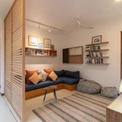 Secluded reading nook with a corner coach, floating book shelves and a side window view of Villa De L'Ocean garden.