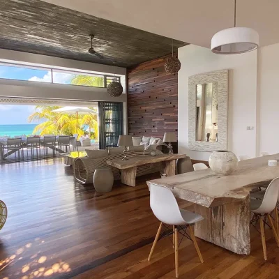 Dining area with wooden flooring and a large wooden table that opens onto ocean views via large sliding doors.