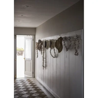 Entrance passageway to Beach House Zonnestraal with white wooden cladding and decorative seashell wall art.