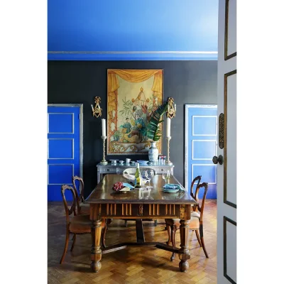 Villa Toscana dining room with parquet flooring, deep blue ceilings and black walls with a golden art mural, and an antique mahogany dining table and chairs.