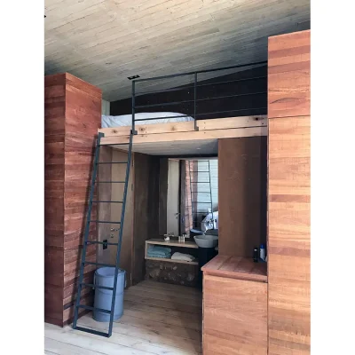 Bedroom suite in Witklipfontein eco lodge with wooden cladded walls, and an elevated bed with a ladder situated above an ensuite bathroom nook with a washbasin and mirror.