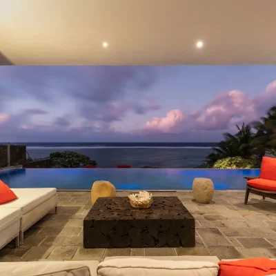 Outdoor seating area overlooking infinity pool and sunset.