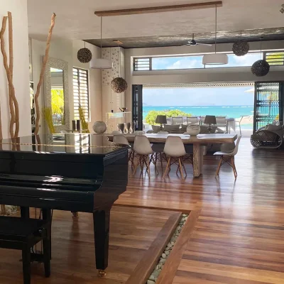 Statement piano situated in an open plan lounge and dining room that overlooks ocean views.