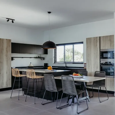 Modern kitchen with an island, and brown and charcoal finishes that reflect in the cabinets, counters, flooring and bar stools. Black River Penthouse.