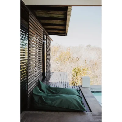 Patio with an attached wrap around deck with two green loungers shaded by a pergola and overlooking the Blogck swimming pool.