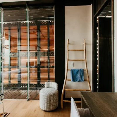 The View bedroom suite with hard wood floors and beige washed walls with stack back glass doors that open onto a deck enclosed by wooden shutters.