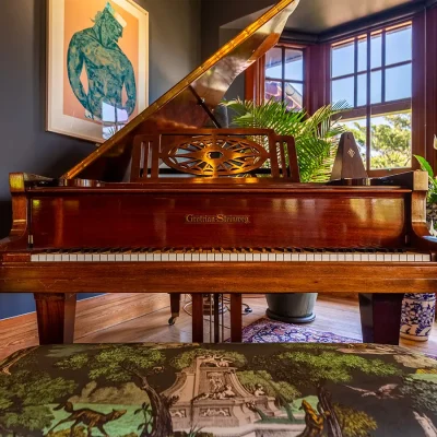 Wooden Grotrian Steinweg Grand Piano with backdrop of open wooden sash windows. House Nouveau.