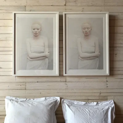 Bedroom walls compromised of palette wood, bleached with lime, wall art and white linen pillows.