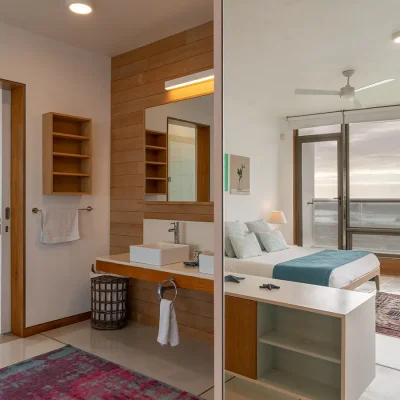 Villa De L'Ocean en-suite bathroom with twin basins against a wooden panelled wall, and a separate toilet.