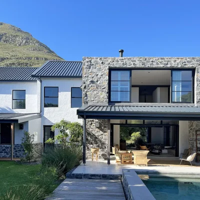 Pinebeach home set on two voluminous levels of polished white and exposed stone walls, tall glass industrial doors and windows with a luscious front garden and swimming pool.