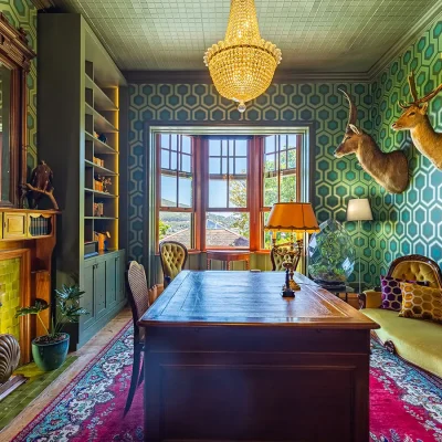 Writing desk in study with fireplace and blue green honeycomb wallpaper. House Nouveau.