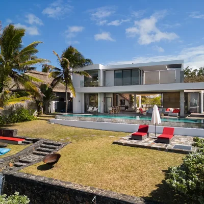 Mauritius villa overlooking the garden with infinity pool and pool chairs, and a leisurely seating area.