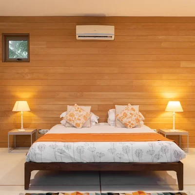 Luxury bedroom in Villa De L'Ocean with a queen bed against a wooden panelled wall with an air conditioner.