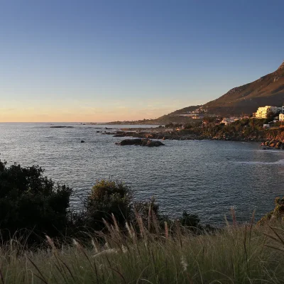 Sunset over Camps Bay, highlighting the magnificent Lion's Head mountain slopes, and lighting up the faces of costal properties.