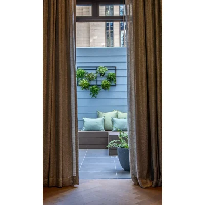 Beige linen curtains opening ceiling to floor double doors that open onto a secluded