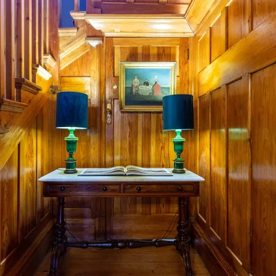 Wooden staircase nook with wooden table and decorative lamps. House Nouveau.