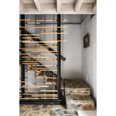 Contemporary staircase with decorative wooden slats that expose a simple wooden stair case and the original rough stone flooring and clay walls of Buffelsdrift.