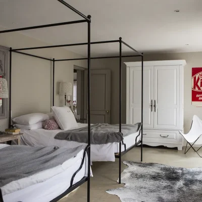 Family suite in Beach House Zonnestraal with twin black metal framed four poster beds with crisp white linen and decorated with shades of grey and red reflecting in the pillows and 'KitKat' wall art.