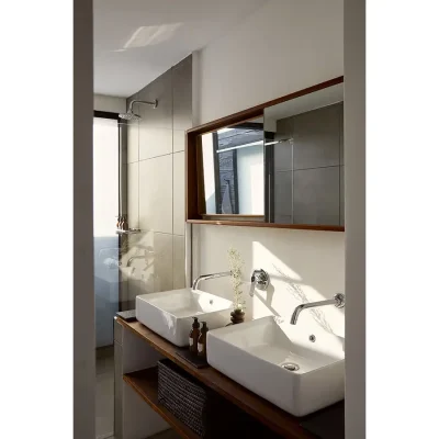 Bathroom in the Herenberg with ceramic double washbasins, wooden framed mirrors and a glass enclosed shower.