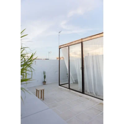 Secluded outdoor terrace with whitewashed walls and surrounded by glass stack back doors. Casa Piana.