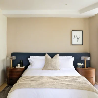 Light bedroom with large sliding doors, an en-suite bathroom, and furnished with a double bed with a navy headboard and wooden side tables, and is decorated with crisp, white linen and a cream throw. Ebb Tide.