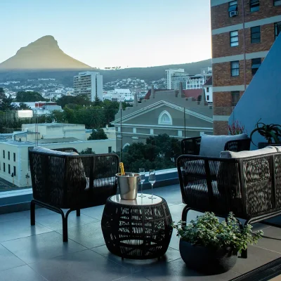 Labotessa Hotel outdoor patio with black wicker armchairs and a sofa facing the city and Lions Head.