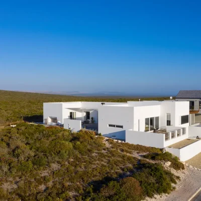 Feng Shui, an elevated light, white home perched on a property surrounded by west coast vegetation.