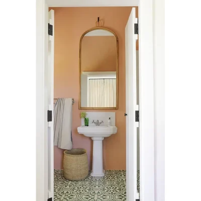 Buchubos Villa bathroom with orange wall, decorative flooring, a ceramic washbasin and mounted wall mirror.