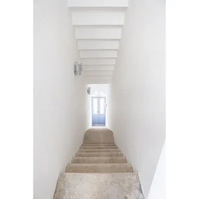 Stone stair case cocooned by whitewashed walls leading you to large blue wooden entrance door of Casa Piana.