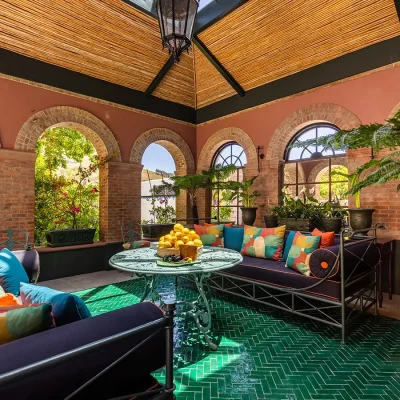 Indoor outdoor sitting area with large arches, tropical greenery and bright green tiled flooring. House Nouveau.