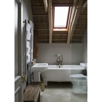 Victorian style bath tub positioned below an angled thatched roof with a skylight in Beach House zonnestraal bathroom.