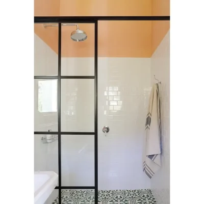 Bathroom with white tiled wall and glass enclosed shower.