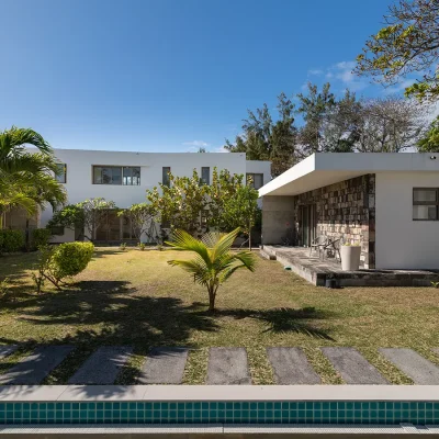 Private stone cottage in Villa De L'Ocean garden with green lawn, palm tree's and an extensive lap pool.