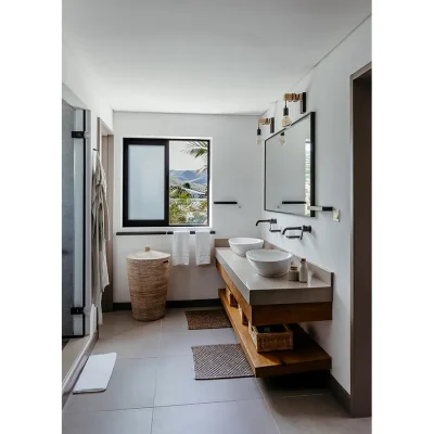 Twin granite washbasins add luxury to Black river Penthouse bathroom with a mirror, grey tiles and a stained glass window that opens onto the mountain range.