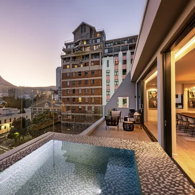 Top-floor presidential suite at Labotessa Hotel with large stack back doors that open the living area onto a deck with a mosaic plunge pool with views of the city and Lions Head.