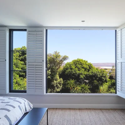 Pinebeach main bedroom with views with large stack-back windows that expose views of the luscious green trees and Norrdhoek beach.