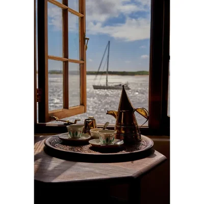 A tea tray set in front of a wooden exposing ocean views and a passing dhow. Peponi Hotel.