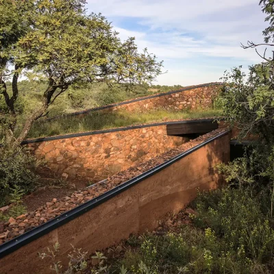 Elongated stone and clay walls surrounded by natural vegetation.