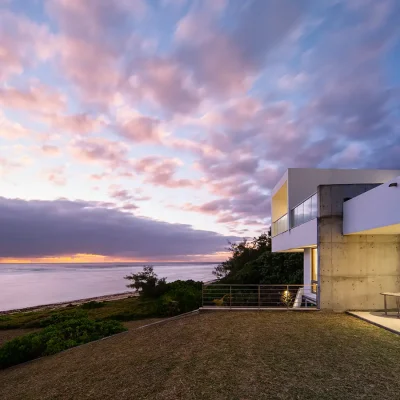 Modern Mauritius villa, Villa De L'Ocean with a rolling lawn and ocean views with a pink hue sunset.