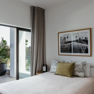 Crisp yet simple Black River Penthouse bedroom with white bed linen and tropical prints, and large sliding doors that open onto the terrace.