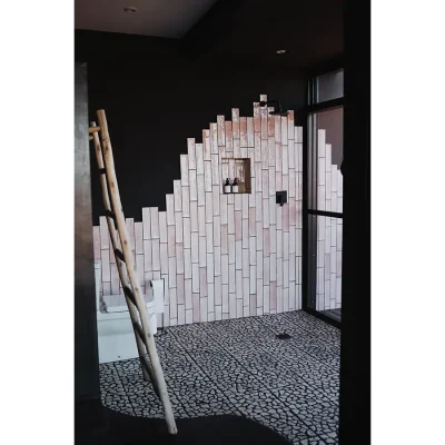 Large walk in shower with pink hue wall tiles, cobbled flooring and a large window. The Blogck.