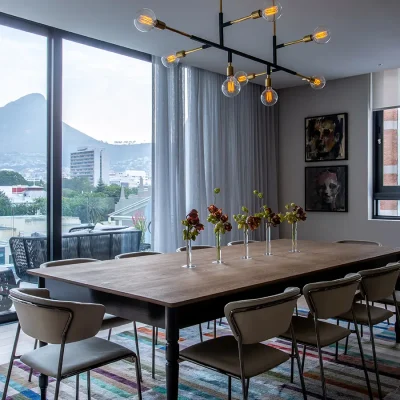 Sleek wooden dining table with leather armchairs that compliment the clean beige walls, and large stack back glass doors that open onto the balcony with mountain views. Labotessa Hotel.