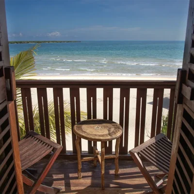 Wooden shutter doors that open onto a secluded balcony with ocean views and a wooden table and chairs. The Fort.