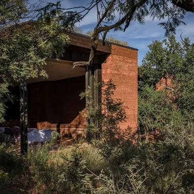 Open plan bedroom suite with a spacious white linen bed that overlooks the bushveld via large stack back doors. Witklipfontein eco lodge.