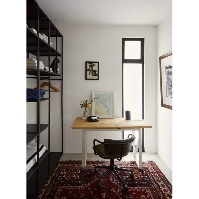 Cosy study space with red Persian rug, an extensive, metallic bookcase and a simple wooden desk with a leather armchair.