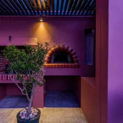 Outdoor brick fireplace and pizza oven with purple coloured walls. House Nouveau.