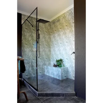 Manor House ensuite bathroom with large glass enclosed shower and decorative green floor and wall tiling.