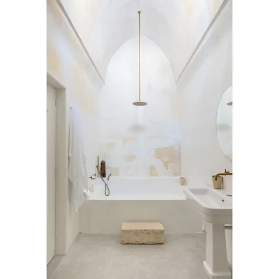 Casa Piana bathroom with whitewashed walls, an arched ceiling, and a large built in bath and ceramic washbasin.